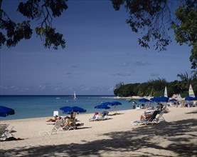 BARBADOS, St James, "Sandy Lane beach, sunbathers, blue umbrellas, overhanging trees "