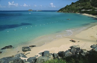 WEST INDIES, St Martin, Grande Case Beach, Wide view of the bay with man sunbathing on sun lounger