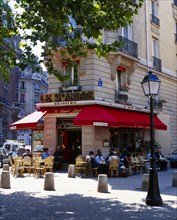 FRANCE, Ile de France, Paris, Cafe on street corner with red awning and outside tables street lamp
