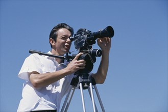 INDUSTRY, Media, Male film cameraman with old style camera on tripod