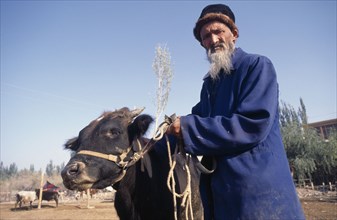 CHINA, Xinjiang, Kashgar, Man with a cow at the Sunday Market