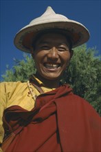 TIBET, Lhasa, Portrait of smiling monk wearing hat