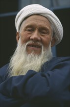 CHINA, Xinjiang, Kashgar, White bearded smiling Kazakhi man in blue wearing white turban