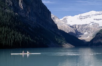CANADA, Alberta, Banff National Park, Canoeist on Lake Louise with a backdrop of snow covered sheer