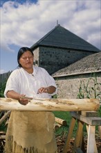 CANADA, Ontario, Sainte Marie, Ojibway Indian woman stripping the bark from trees