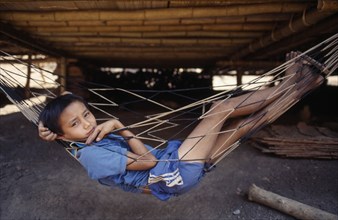 THAILAND, North, Mae Sai , Karen refugee boy lying in hammock