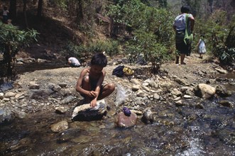 THAILAND, North, Mae Sariang, Karen refugee boy washing by a rocky stream
