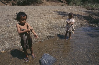 THAILAND, North, Mae Sariang, Two young Karen refugee children washing at the waters edge