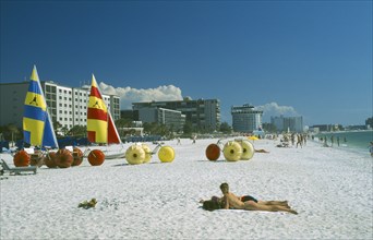 USA, Florida, St.Petersburg, "Sunbathers, Hobbie cats and pedalos on white sand beach with city