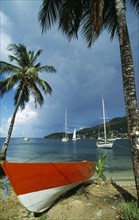 WEST INDIES, Grenadines, Union Island, Orange and white boat on coconut palm tree fringed beach