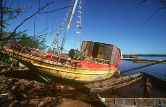 FRENCH GUIANA, St Laurent, Beached fishing boat with boy in shallow water