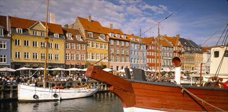 DENMARK,  , Copenhagen, Boats on Nyhavn Canal with pavement cafes and waterside buildings behind.