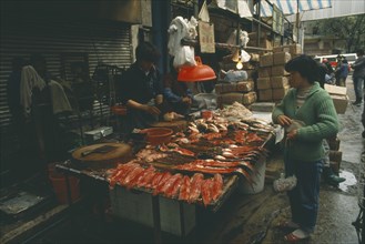 CHINA, Guangdong, Guangzhou, Fish stall in the market with vendor and customer.