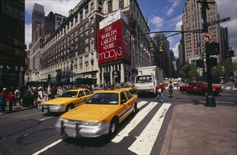 USA, New York, Manhattan, Macy's department store with taxis and pedestrians in a busy street