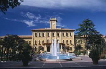 ITALY , Emilia Romagna, Cattolica, Elegant yellow town hall building with trees and a fountain in