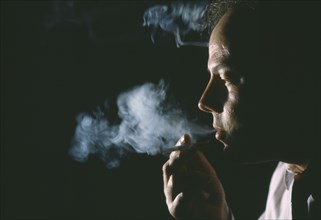 HEALTH, Smoking, Man exhaling smoke from cigarette.