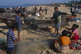 INDIA, Goa, Calangute, People including family group working on the beach sorting fishing nets