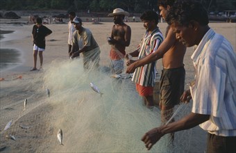 INDIA, Goa, Calangute, Men working on the beach sorting fishing net