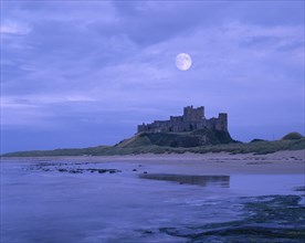 ENGLAND, Northumberland, Bamburgh Castle, View across beach at low tide towards the castle against