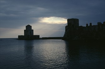 GREECE, Peloponnese, Methoni, View across the sea towards fortress ruins lit by evening sun rays