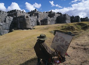 PERU, Cusco Department, Sacsayhuamán, Artist at his easel infront of the Inca walls in ruined