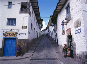 PERU, Cusco Department, Cusco, View up a narrow street between white painted houses.   Woman and
