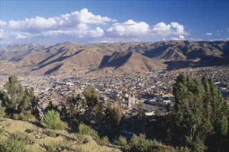 PERU, Cusco Department, Cusco, View over trees and the city of Cusco to the mountains beyond.