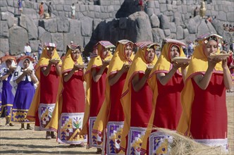 PERU, Cusco Department, Sacsayhuaman, Parade of women offering  food at Inti Raymi.  Inca walls