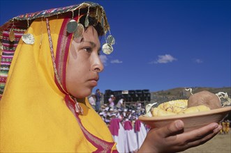 PERU, Cusco Department, Cusco, "Woman in traditional headress carrying an offering of food during