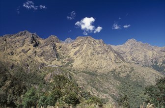 PERU, Cusco Department, The Inca Trail, View over trees towards the mountains against a blue sky.