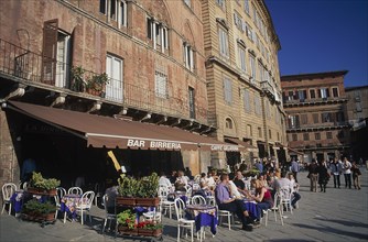 ITALY, Tuscany, Sienna, The Piazza del Campo with people sitting at tables under umbrellas outside