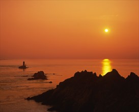 FRANCE, Brittany, Finistere, Near Audierne.  Pointe du Raz at sunset.  Rocks silhouetted against an
