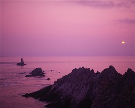 FRANCE, Brittany, Finistere, "Near Audierne.  Pointe du Raz at sunset.  Rocks silhouetted against a