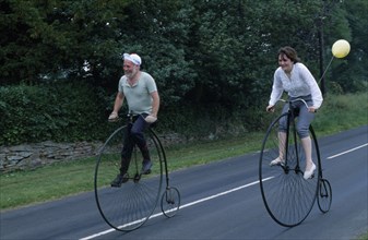 20005306 SPORT Cycling Bikes Man and woman riding old Penny Farthing Bicycles
