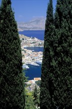 GREECE, Dodecanese, Symi, Gialo.  The town and harbour partly viewed between trees in the