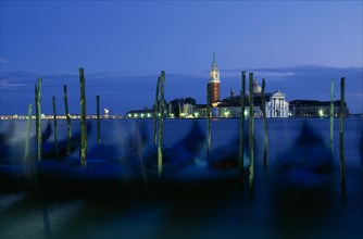 ITALY, Veneto, Venice, Line of gondolas in motion with the Church of San Giorgio behind.