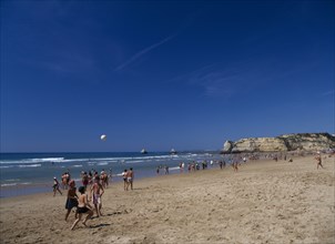 PORTUGAL, Algarve, Praia da Rocha, View along beach with children playing beach football.