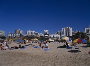 PORTUGAL, Algarve, Praia da Rocha, View of beach with people sunbathing and clifftop hotels behind