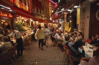 BELGIUM, Brabant, Brussels, People sitting at outside tables in narrow street lined with