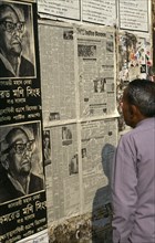Bangladesh, Dhaka, Man reading wall mounted newspaper.