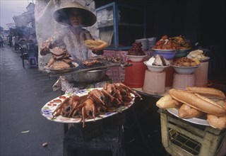 VIETNAM, Mekong Delta, Vinh Long, Woman cooking various meat products at market stall.