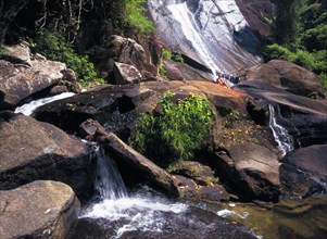 MALAYSIA, Kedah, Langkawi, Telaga Tujuh Seven Wells Waterfall with female tourist sitting on rocks
