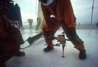INDUSTRY, Tools, Drill, Man using a power drill on board a ship in  Indonesia.