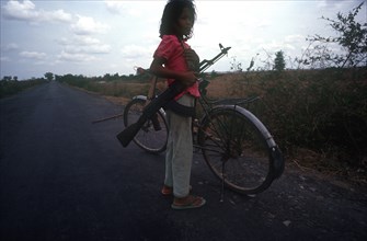 CAMBODIA, Kompong Thom, Ten year old girl standing on the Route 6 roadway beside her bicycle