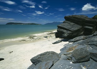 MALAYSIA, Kedah, Langkawi, Pantai Tengah beach looking towards Pulau Rebak Besar island with rocks