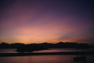 MALAYSIA, Kedah, Langkawi, Sunrise over Pulau Dayang Bunting island with schooner moored in the