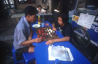 THAILAND, Bangkok, Couple playing a board game at a streetside cafe.
