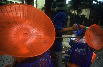 VIETNAM, Hanoi, Street vendor with display of coloured plastic baskets and utensils.
