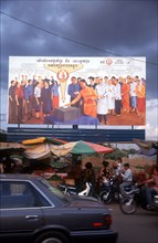 CAMBODIA, Phnom Pehn, Election poster with line of stalls selling fruit along the roadside in front