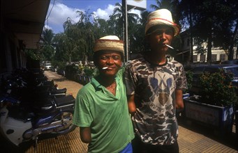 CAMBODIA, Phnom Pehn, Veteran amputees smoking cigarettes outside the Hotel Monorom.